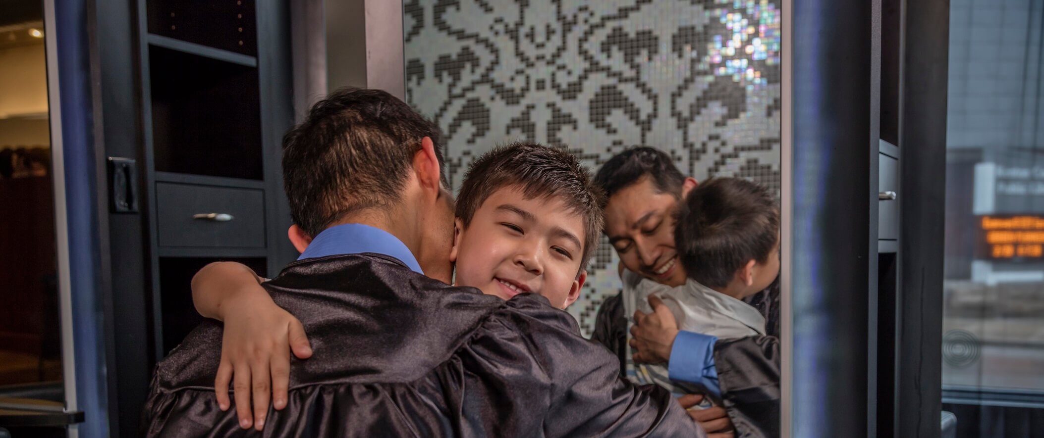 father in graduation robe hugging son