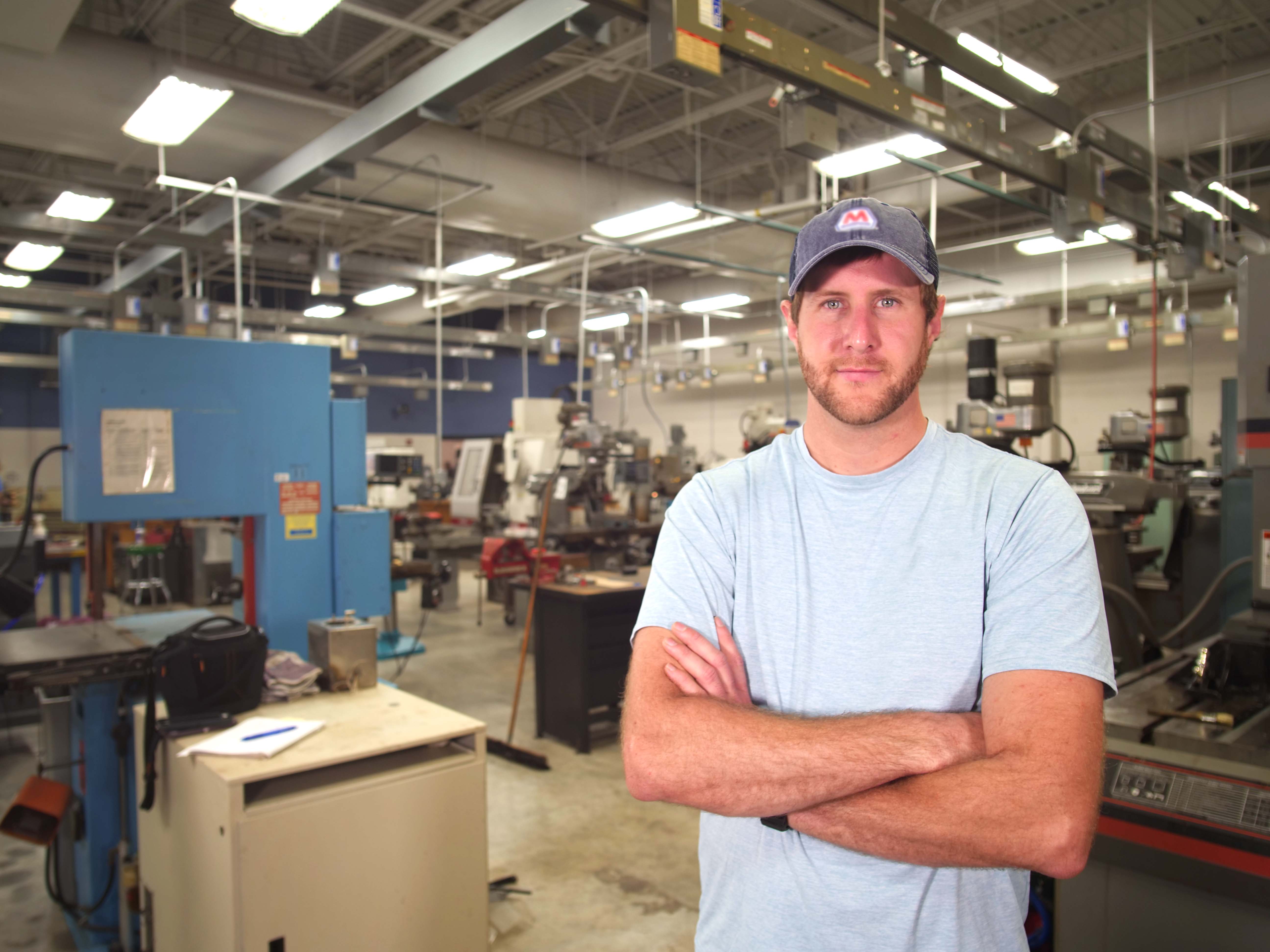 Student standing in manufacturing facility