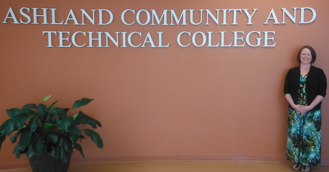 Student Support Services Director and advisor, Megan Horne stands in front of the ACTC logo in the foyer on the Technology Drive Campus.