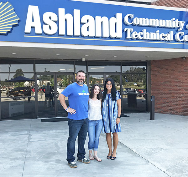 A representative from Build Ashland stands with scholarship recipient and ACTC's director of resourse development in front of the college on a sunny day
