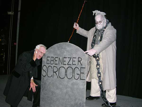 Marley's Ghost shows Scrooge his tombstone.