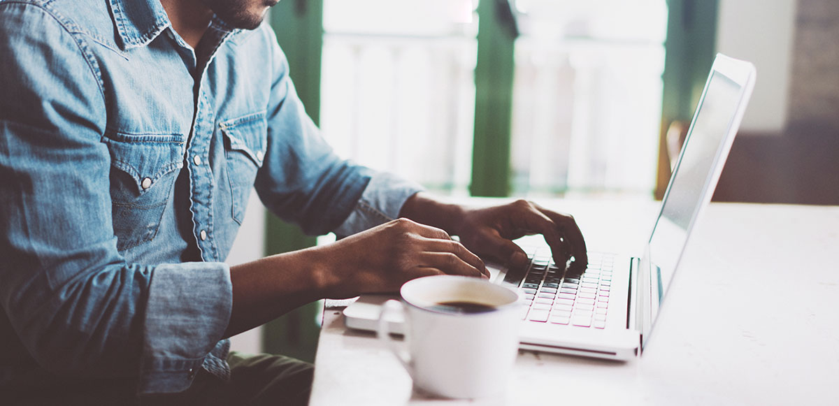 african american male sitting at laptop with coffee